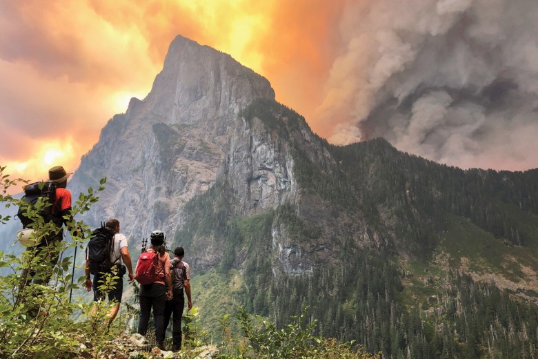 Hikers fleeing from a nearby peak watch the Bolt Creek Fire burn up the backside of Washington’s Baring Mountain.  