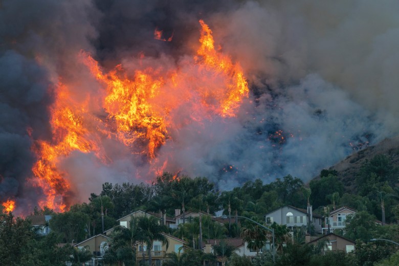 Flames rise near homes during the Blue Ridge Fire on Oct. 27, 2020, in Chino Hills, California