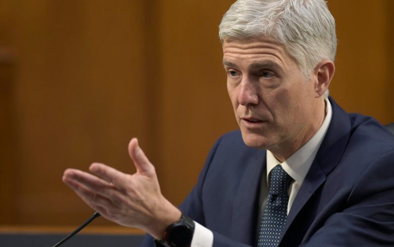 Gorsuch, seated, gestures during testimony.