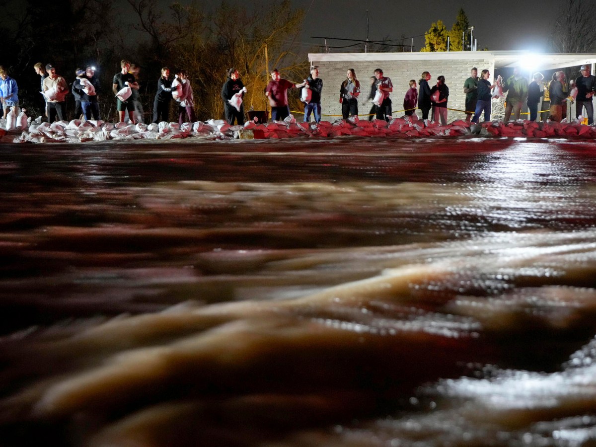 People pass sand bags to protect homes from the rising flow of Emigration Creek through Wasatch Hollow Park, Salt Lake City, on April 12, 2023.